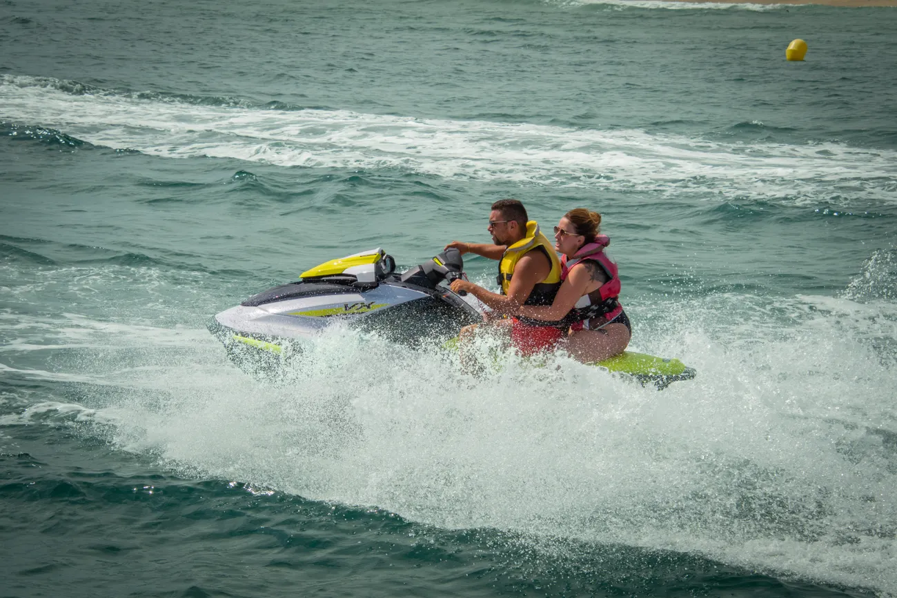 Pessoas aproveitando um jet ski junto à costa, imagem de referência